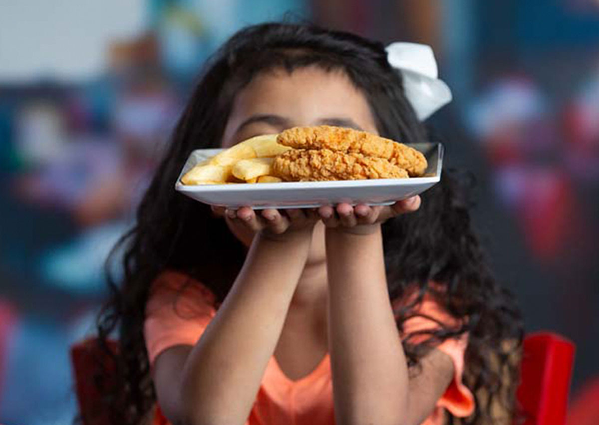 Young Guest holding up a plate of Cluck-a-doodles and Bottomless Steak Fries.