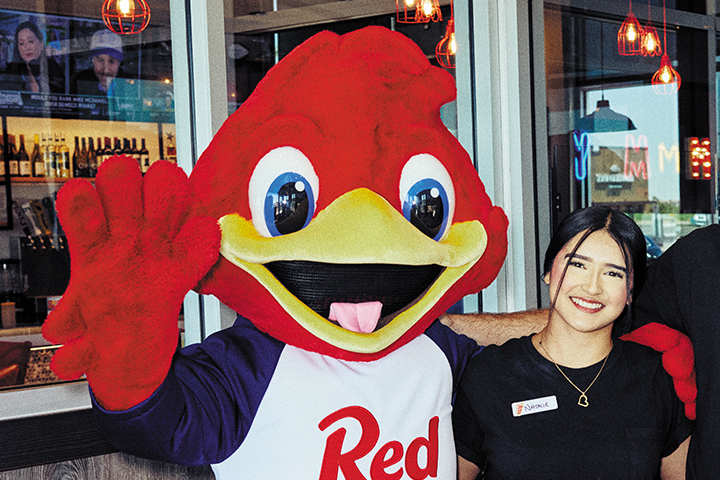Red Mascot waving with another employee