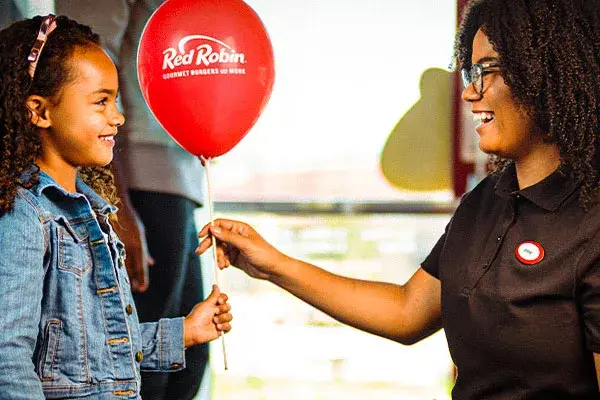 Team Member giving a balloon to young Guest