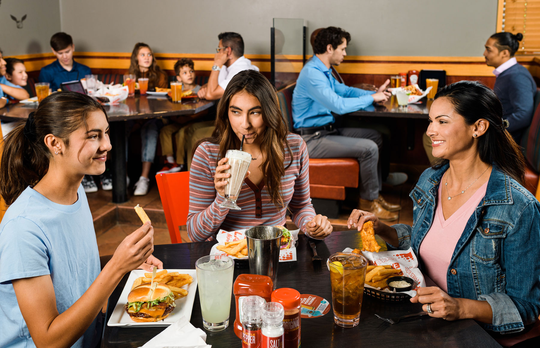 Family enjoying burgers, milkshakes and beverages around table in restaurant